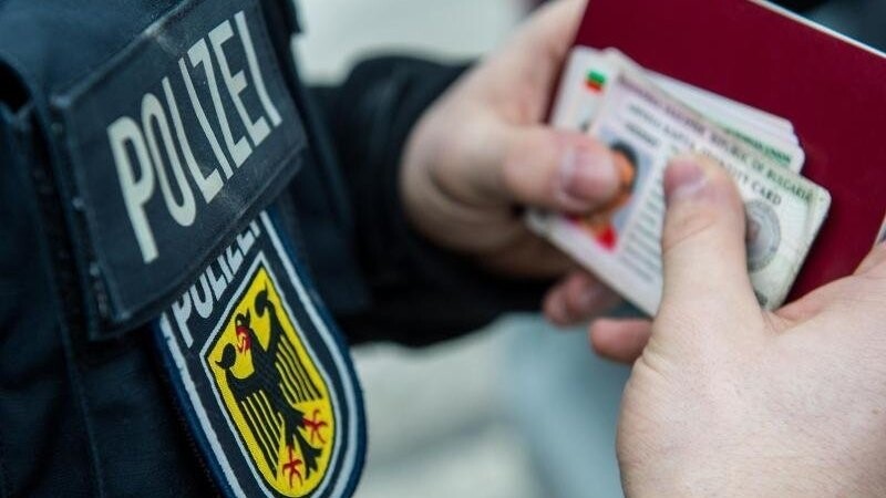 Ein Beamter der Bundespolizei hält bei einer Kontrolle mehrere ausländische Ausweise in den Händen. (Symbolbild)