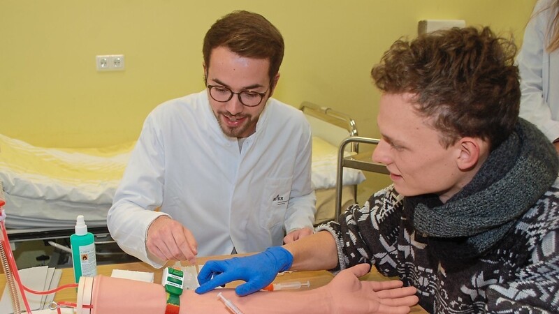 Dieser Arm ist schon oft gepikst worden: Medizinstudent Lucas Rüffer übt die Blutabnahme. Dahinter Tutor Johannes Gludowatz.