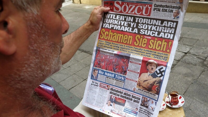 Ein Mann liest in Istanbul die türkische Tageszeitung "Sözcü", die Bundeskanzlerin Merkel in Naziuniform und Hitlerbart auf der Titelseite abbildet.