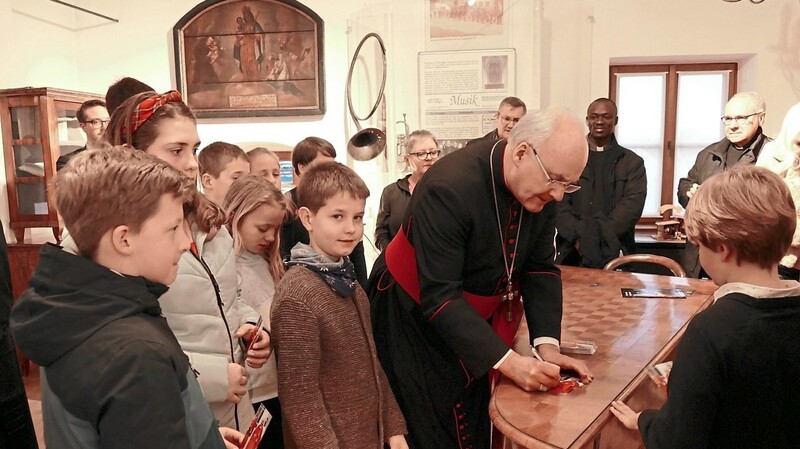 Der Bischof schrieb einige Autogramme.