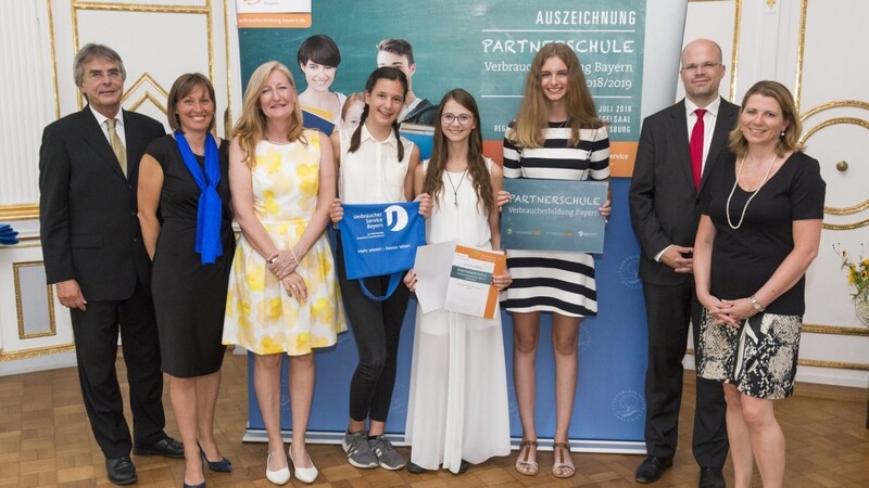 Die zukünftige Schulleiterin Angela Schöllhorn (dritte von links) mit den ausgezeichneten Schülerinnen des RSG (Mitte) sowie Vertretern der Regierung und des VerbraucherService Bayern.