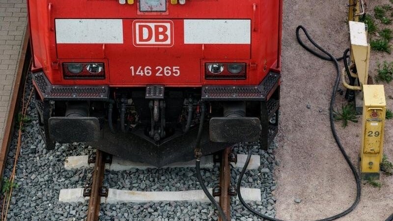 Eine Lokomotive der Deutschen Bahn steht vor dem Kieler Hauptbahnhof auf den Gleisen und ist an Versorgungsleitungen angeschlossen.