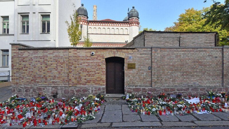 Blumen und Kerzen stehen neben der Tür zur Synagoge in Halle, vier Tage nach dem rechtsextremistischen Anschlag auf die Gemeinde.