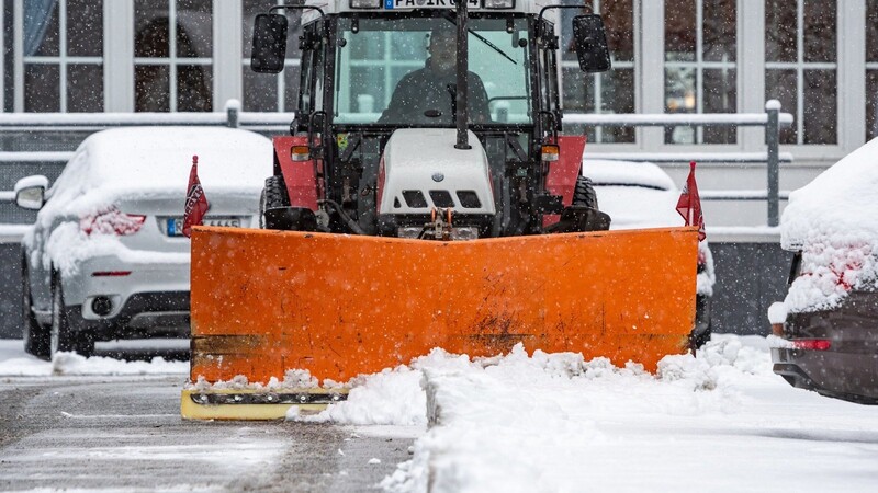 Mit einem Traktor wird Neuschnee von einem Parkplatz in Sankt Englmar geräumt.