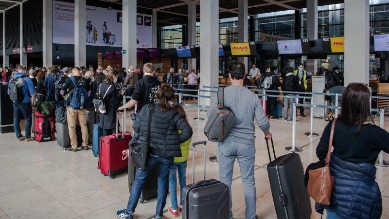 Reisende stehen am Flughafen BER vor einem Check-in-Schalter. Corona-Regeln beschränken weiterhin das freie Reisen.