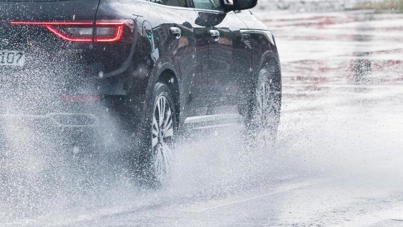Ein Auto fährt bei Starkregen über eine Straße. (symbolbild)
