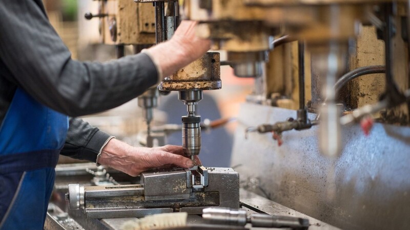 Ein Mitarbeiter bedient in einer Produktionshalle eine Maschine zur Verarbeitung von Metall.