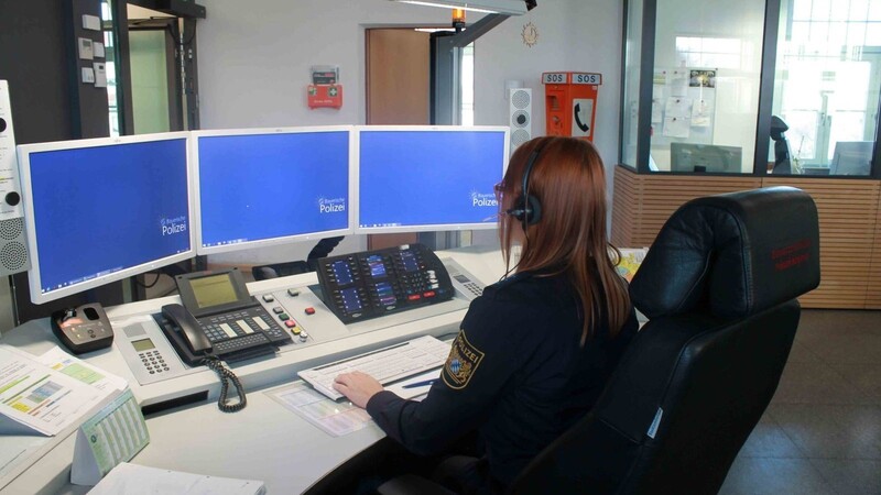 Das ist Theresas Arbeitsplatz in der Einsatzzentrale des Polizeipräsidiums Niederbayern in Straubing. Damit sie die Hände frei hat, ist ihr Headset direkt mit dem Telefon verbunden, an dem die Notrufe eingehen. So kann sie gleichzeitig den Einsatz am Computer anlegen. Aus Datenschutzgründen sieht man auf dem Foto nur den Bildschirmhintergrund.