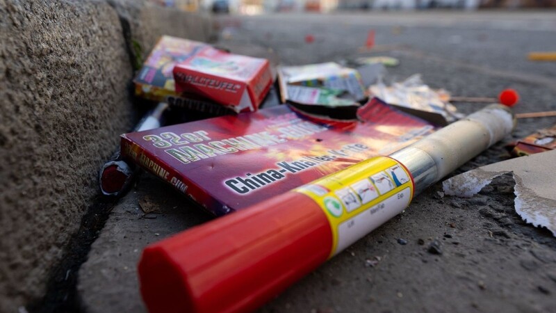 Verpackungen und abgebrannte Feuerwerkskörper liegen auf einer Straße.