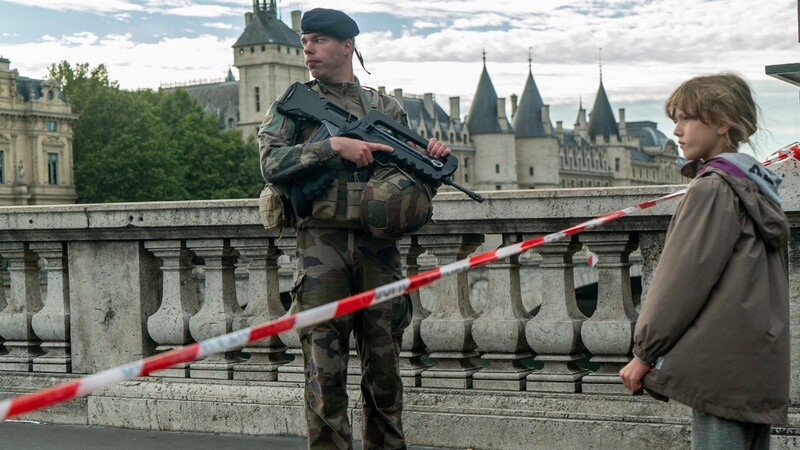 Ein Mädchen steht vor einem bewaffneten Soldat in einer versperrten Straße nahe der Pariser Polizeipräfektur.