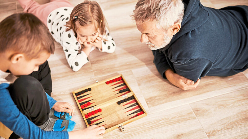 Spielen verbindet die Generationen - hier spielen Enkel mit ihrem Opa Backgammon.