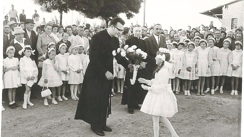 Ein Mädchen überreicht dem Neupriester Willibald Hirsch einen Blumenstrauß als Willkommensgruß.