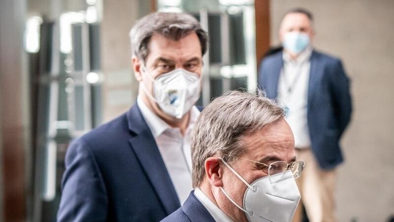 Markus Söder (CSU, hinten) und Armin Laschet (CDU) gehen zu einer Pressekonferenz. Foto: Michael Kappeler/dpa/Archivbild
