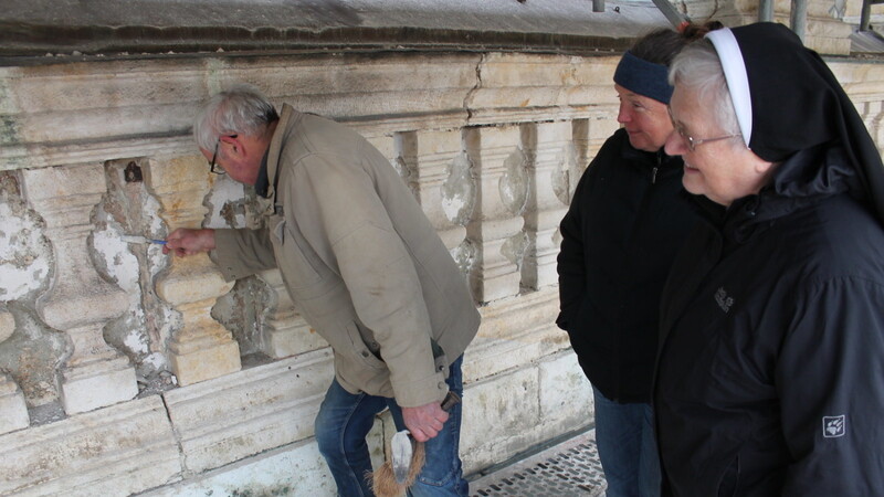 Oberin Schwester Judith Reis und Architektin Monika Dietrich schauen Steinrestaurator Georg Doreth über die Schulter.