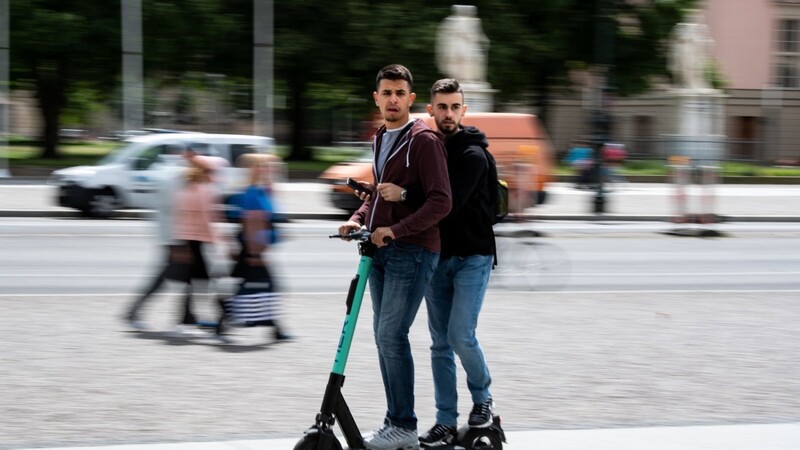 Zwei Touristen fahren auf einem E-Roller durch Berlin-Mitte.