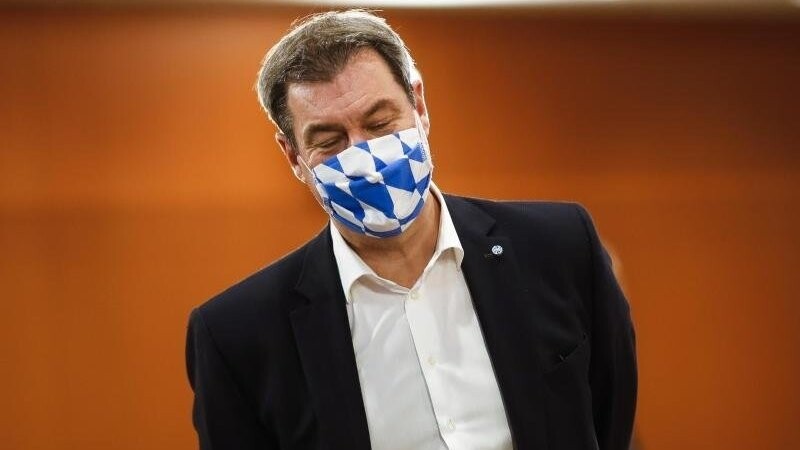 Markus Söder, Ministerpräsident von Bayern, trägt eine Gesichtsmaske mit dem weiß-blauen Rautenmuster Bayerns.