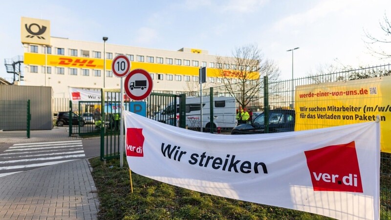 Ein Banner mit der Aufschrift "Wir streiken" hängt vor einem Gebäude des Paketdienstleisters DHL in Lahn.