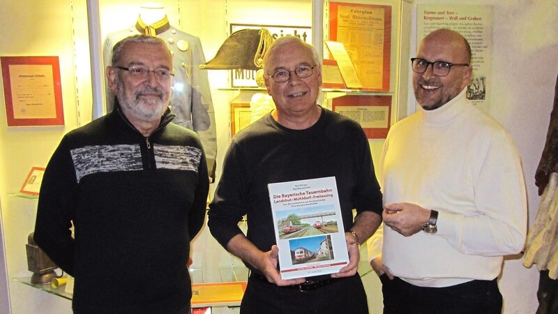 Zusammen mit Stephan Priller, dem Vorsitzenden des Heimatvereins (rechts) und Vorstandmitglied Rudolf Stadlöder präsentiert Karl Bürger (Mitte) das Buch vor der Eisenbahn-Vitrine im Museum.