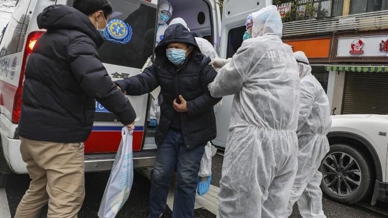 Krankenhausmitarbeiter in Wuhan helfen einem Patienten aus einem Krankenwagen.