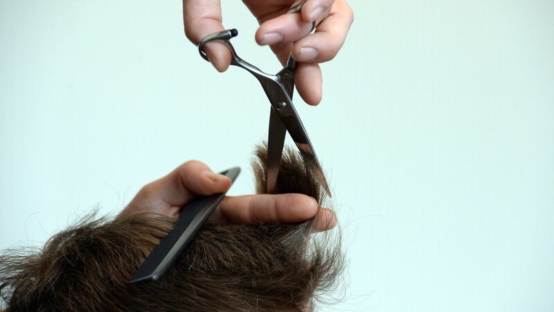 Ein Friseur schneidet die Haare. (Symbolbild)