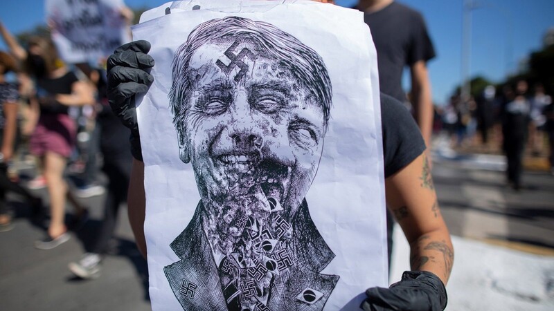 Einige Demonstranten werfen dem brasilianischen Präsidenten wegen seiner Tatenlosigkeit Genozid vor. Auf diesem Protestplakat verschwimmt Bolsonaros Gesicht mit dem Hitlers.