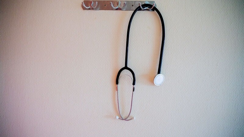 Ein Stethoskop hängt an einer Garderobe.