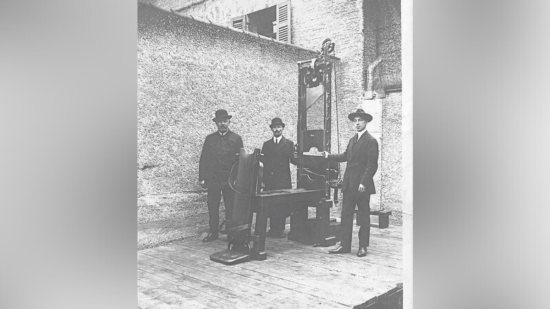 Der letzte Scharfrichter Johann Reichhart (Mitte) mit seinen Gehilfen vor der Guillotine, auf der er die meisten Hinrichtungen vollstreckte.