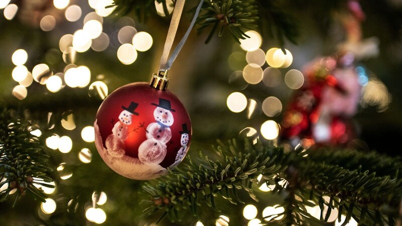 Eine Weihnachtskugel hängt an einem Weihnachtsbaum mit einer Lichterkette.