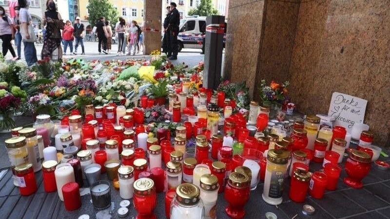 Blumen und Kerzen liegen nach einer Messerattacke vor einem geschlossenen und abgesperrten Kaufhaus.