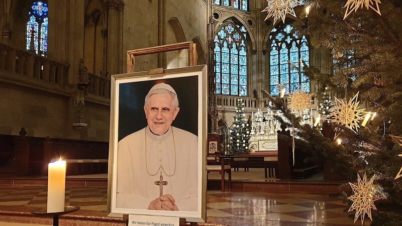 Ein Porträtbild von Benedikt XVI. wurde im Chorraum des Regensburger Doms neben einer brennenden Kerze aufgestellt. Gläubige können davor beten.