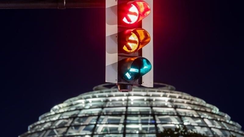 Rot-gelb-grün - eine Ampel leuchtet vor der Kuppel des Reichstagsgebäudes (in einer Langzeitbelichtung) in allen drei Phasen. Noch stecken die Koalitionsverhandlungen zwischen SPD, Grünen und FDP in der inhaltlichen Phase.