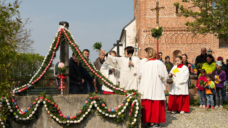 Der Brunnen vor der Sankt Marien-Kirche in Preisenberg ist mit Zweigen und bunten Eiern geschmückt. Pastoralassistentin Yvonne Achilles segnete den Brunnen und die Palmbuschen.