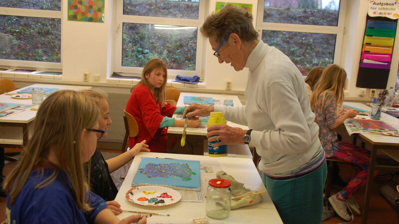 Die freischaffende Malerin Maria Thurner leitet die Kinder an, ein abstraktes Bild mit Acrylfarben zu malen. Statt "zu fisselig und zu genau", sollen die Kinder lernen, spontan mit Pinsel und Farbe umzugehen: "Auf diese Weise entstehen die schönsten Bilder."