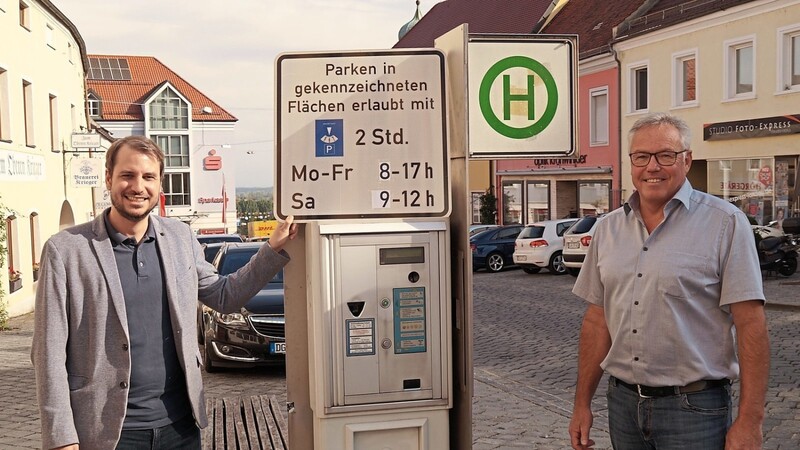 So sollen die neuen Schilder einmal aussehen: Bürgermeister Matthias Kohlmayer (links) und Alois Streifeneder, Sachgebietsleiter Straßen- und Verkehrswesen, vor einem der bald ausgedienten Parkscheinautomaten.
