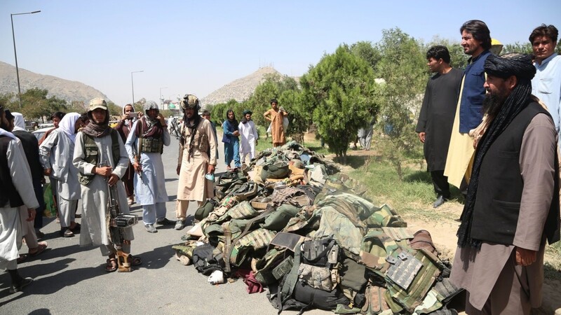 Mitglieder der Taliban stehen neben den Habseligkeiten von afghanischen Sicherheitssoldaten. Die afghanische Armee hat kaum gekämpft und sich den Taliban ergeben.