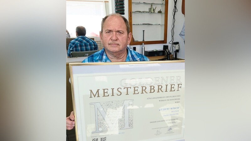 Stolz präsentiert Friseurmeister Hubert Rösch den Goldenen Meisterbrief.