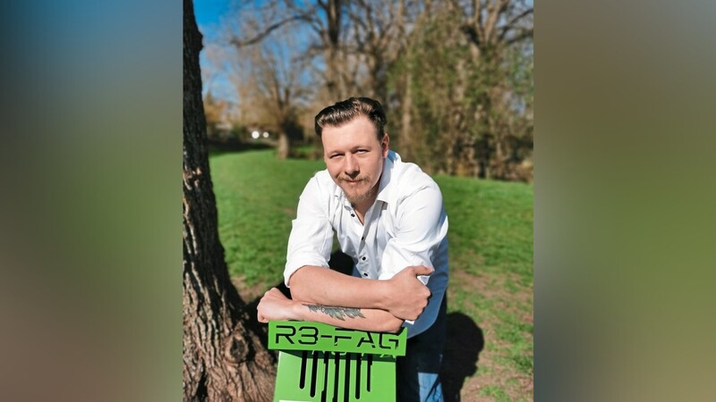 Florian Eder (31) lehnt auf seinem blattgrünen Sammelaschenbecher. Die so gesammelten Zigarettenkippen möchte er recyceln.