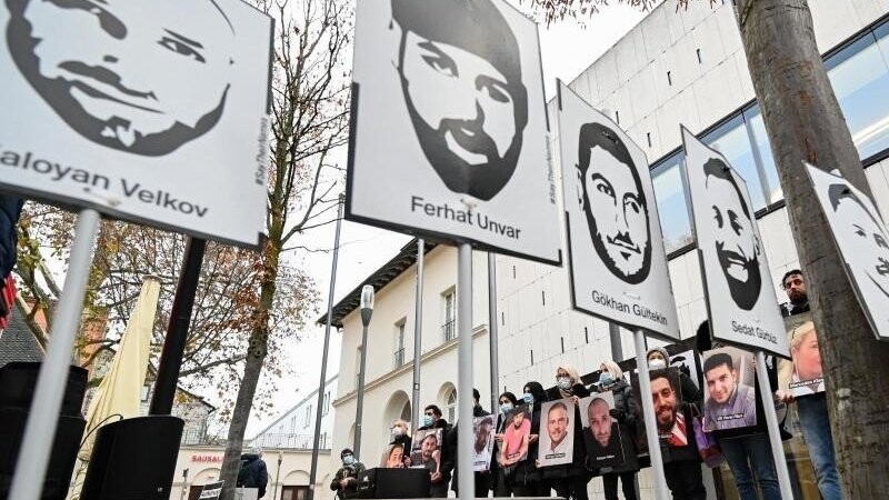 Angehörige der Opfer des rassistischen Anschlags von Hanau 2020 halten bei einer Mahnwache Fotos der Opfer.