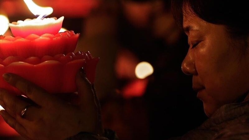 Eine Frau in Peking hält am ersten Tag des chinesischen Mond-Neujahrs eine blütenförmige Kerze.