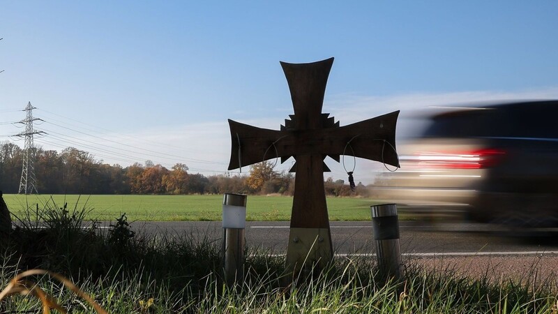 Ein Kreuz steht an einer Landstraße und erinnert an ein Unfallopfer.
