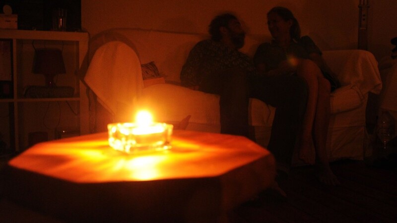 Ein Paar sitzt während eines Stromausfalls bei Kerzenschein in einer Wohnung.