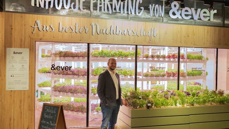Geschäftsführer Daniel Honner steht vor dem vertikalen Gewächshaus im Unterföhringer Markt. Dort können Kunden nun pflückfrischen Salat und Kräuter kaufen - aber nicht selbst ernten.