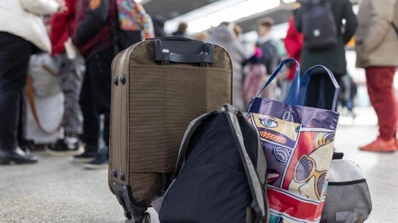 Flüchtlinge aus der Ukraine stehen mit Gepäck am Münchner Hauptbahnhof.