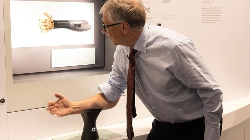 Bill Gates probiert im Deutschen Museum eine Handprothese aus, die sich über die Armmuskeln steuern lässt.
