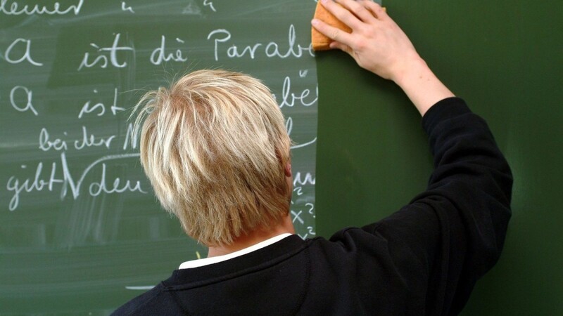 Ein Lehrer wischt während des Mathematik-Unterrichts die Tafel sauber.