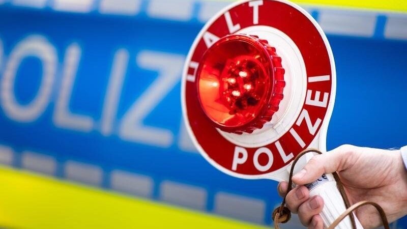 Ein Polizist hält einen Anhaltestab (Winkerkelle) mit der Aufschrift "Halt Polizei". Foto: Marius Becker/Archiv