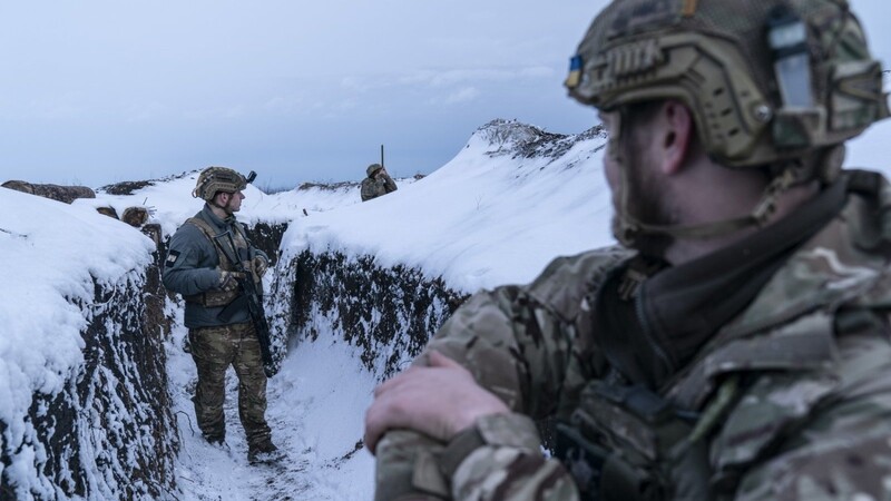 Ukrainische Soldaten gehen entlang eines schneebedeckten Schützengrabens, um ihre Position an der Frontlinie zu bewachen.