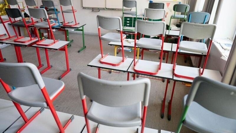 Stühle stehen in einem Klassenzimmer auf den Tischen.