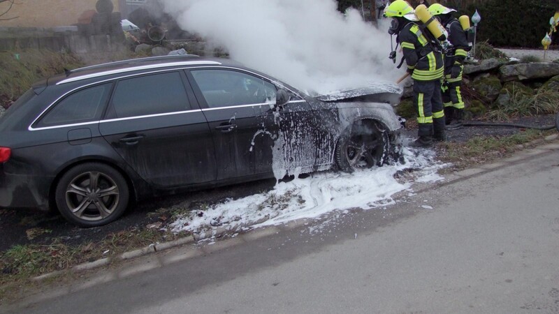 Feuerwehrler löschen das brennende Auto.