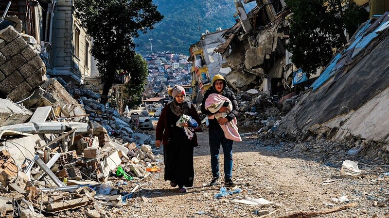 Eine Frau und ein junger Mann gehen durch die Trümmer im türkischen Hatay.